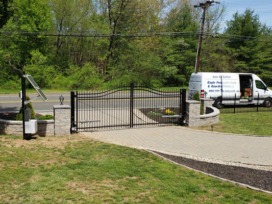 Automated gate installed at the entrance of driveway with Eagle Fence & Guardrail van parked nearby