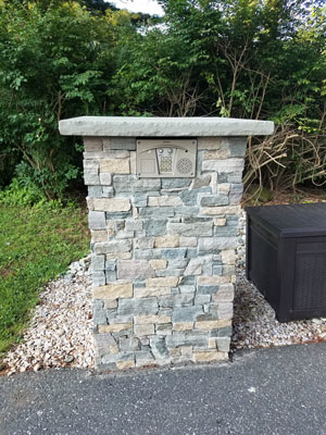 Keypad and communication system installed within stone column near automated gate system in driveway