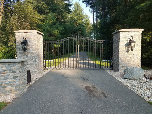 Automated gate installed between two stone columns in driveway