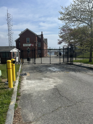 A black chain link security fence and gate around a paved lot.