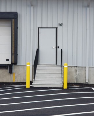 Yellow security bollards in front of a staircase and door