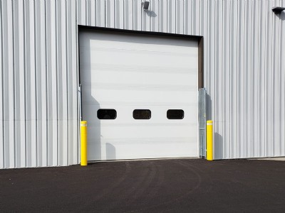 Two yellow security bollards outside of garage door