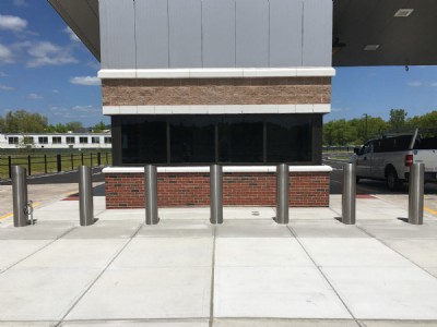 Seven galvanized security bollard posts on cement walkway