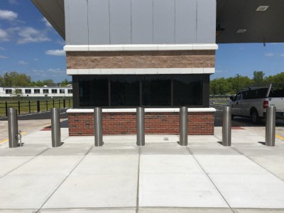 Seven galvanized security bollards on cement walkway