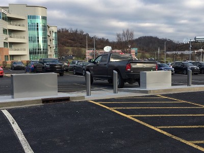 Parking lot with narrow security bollards in between wide security barriers