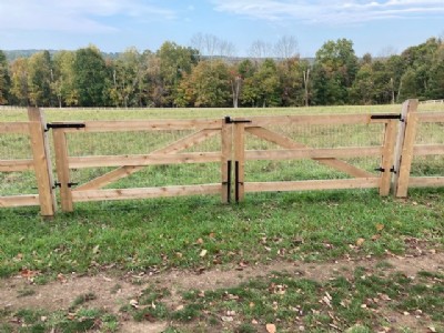 cedar wood fencing gate entrance in a big yard with trees in the background